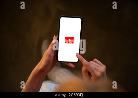 Riga, Latvia - July 3, 2021: Woman holding phone with YouTube logo on the screen Stock Photo