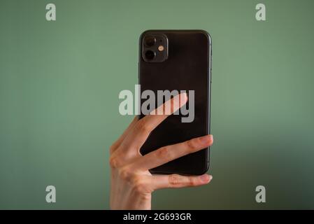 Person holding in hand mobile phone with lens camera, photo isolated on green background Stock Photo