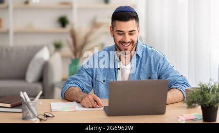 Smiling israeli man working on laptop at home Stock Photo