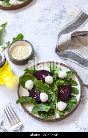 Healthy diet salad with arugula, spinach, beetroot, mozzarella and vinaigrette dressing on a gray stone tabletop. Copy space. Stock Photo
