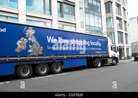 Tesco delivery lorry side view with advert 'We love shopping locally' parked outside Tescos Smithfield supermarket in the City of London England UK Stock Photo