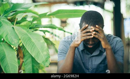 Unhappy african man having puzzled expression, holding hand on his head. Black guy stressting and headache Stock Photo