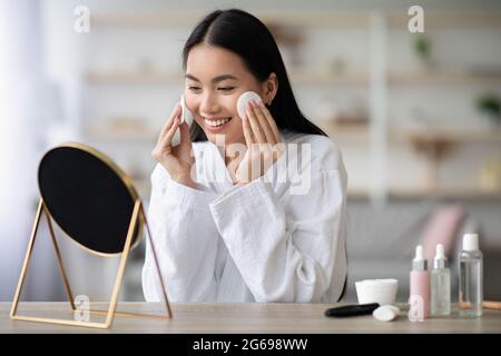 Pretty asian woman cleaning her face with toner Stock Photo