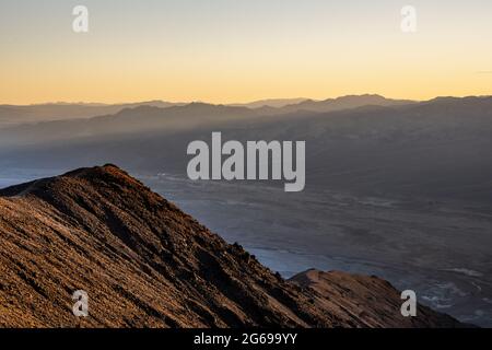 Shafts of Sunlinght Break Over The Ridge As Seen From Dantes View in Death Valley Stock Photo