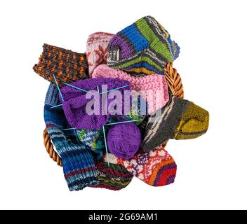 The basket is filled with knitted colored socks and knitting needles on a white background. View from above