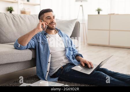 Smiling jew man working and talking on cellphone at home Stock Photo