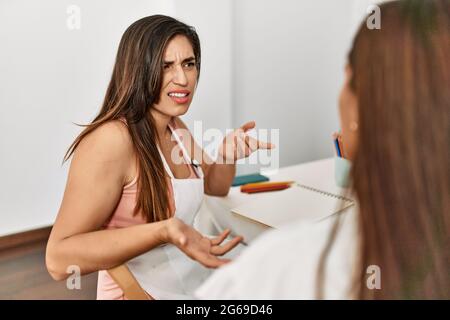 Two latin paint students arguing sitting on the table at art school. Stock Photo