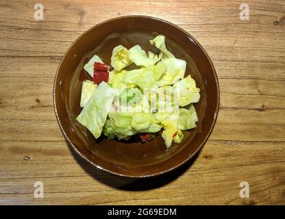 light yellow pickled cabbage with pepper in the bowl under bright light Stock Photo