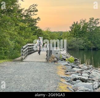 A woman biking on a bike crushed gravel trail along a reservoir in New Jersey. Stock Photo