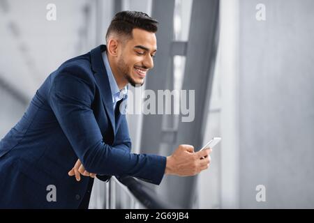Handsome Young Arab Businessman Using Smartphone In Airport While Waiting In Lounge Stock Photo