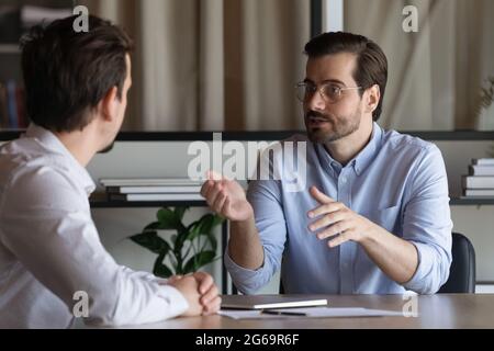 Confident manager in glasses consulting client at meeting in office Stock Photo