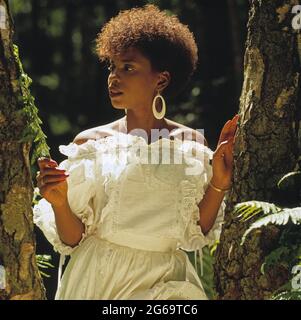 Young woman outdoors by tree.