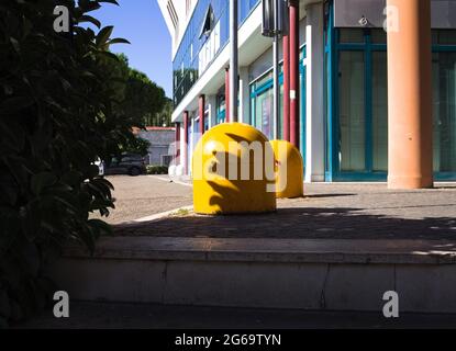 Two yellow colored concrete traffic bollards on the pavement (Marche, Italy, Europe) Stock Photo