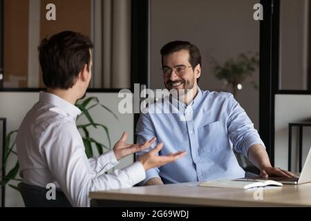 Two happy colleagues talking discussing project sitting at table Stock Photo