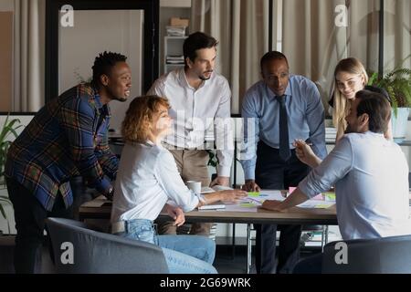 Smiling diverse colleagues brainstorming working with financial documents together Stock Photo