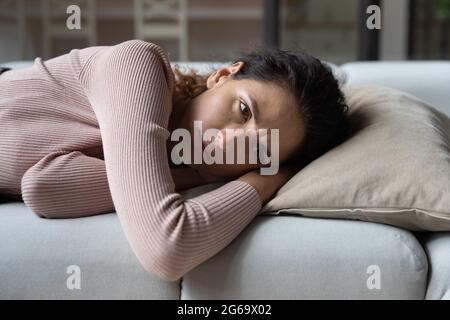 Unhappy young woman feeling bored, lying alone on sofa.