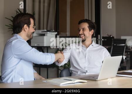 Smiling hr manager shaking successful candidate hand at job interview Stock Photo