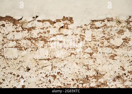 Old traditional limewashed stone wall with peeling plaster, white rustic background or texture Stock Photo