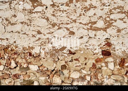 Old traditional limewashed stone wall with peeling plaster, white rustic background or texture Stock Photo
