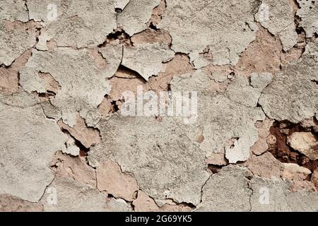 Old traditional limewashed stone wall with peeling plaster, white rustic background Stock Photo