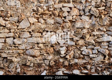 Old traditional limewashed stone wall with peeling plaster, rustic background or texture Stock Photo