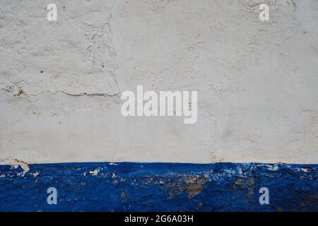 Old plastered with wall with blue indigo skirting board and peeling paint, traditional architecture in La Mancha, Spain Stock Photo