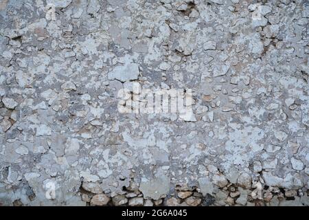 Old traditional limewashed stone wall with peeling plaster, white rustic background or texture Stock Photo