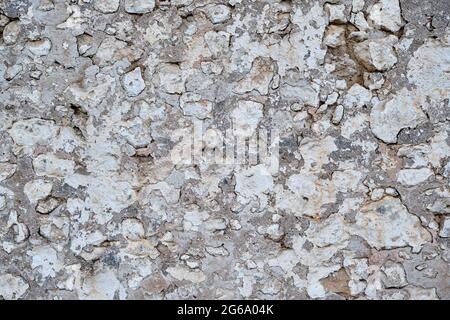 Old traditional limewashed stone wall with peeling plaster, white rustic background or texture Stock Photo