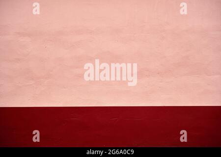 Pink pastel painted concrete wall with dark red red baseboard, abstract background or texture Stock Photo