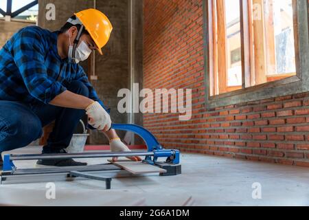 artisan tiler, Industrial tiler builder worker working with floor tile cutting equipment at construction site Stock Photo