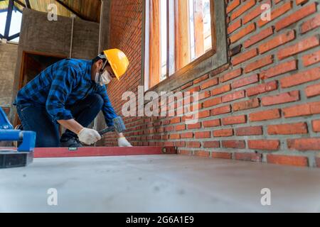 artisan tiler hands working on a new house entrance, local and professional handyman applying tiles at construction site Stock Photo