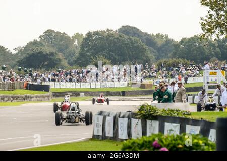 Classic Formula Junior racing cars, vintage racing cars competing in the Chichester Cup at the Goodwood Revival historic event, UK. Spectators. Finish Stock Photo