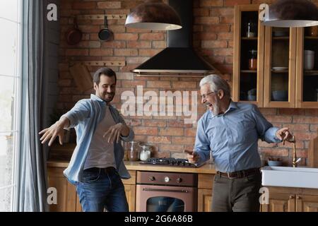 Excited grownup son and senior dad having fun in kitchen Stock Photo
