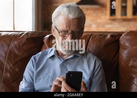 Focused elder 70s man using telemedicine app on smartphone Stock Photo