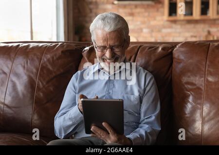 Happy elderly retired 70s man using online app on tablet Stock Photo
