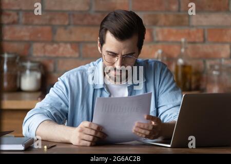 Serious distance employee analyzing statistics, data in paper financial reports Stock Photo