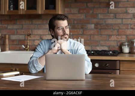 Thoughtful serious remote employee working form home, sitting at table Stock Photo