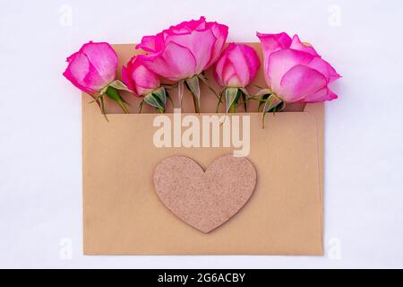 Pink roses in an envelope with a heart isolated on white background Stock Photo