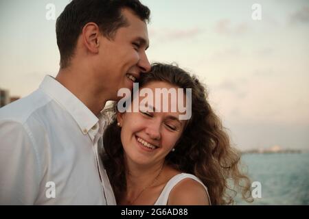 Embracing and smiling heterosexual couple of young adult man and woman Stock Photo