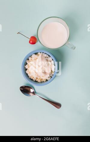 Cottage cheese in a blue bowl with sour cream and honey, a cup with milk. Morning breakfast. Stock Photo