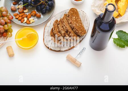 Wine appetizer honey cheese nuts snacks bread grapes fruit on white background. Mediterranean food drinks Ingredients set for dinner. Gastronomy Stock Photo