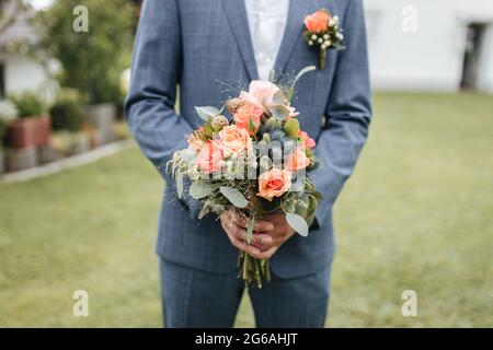 Groom holding bridal flowers close up Stock Photo