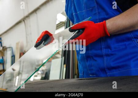 Glass factory, the glazier holds a piece of glass in his hands Stock Photo