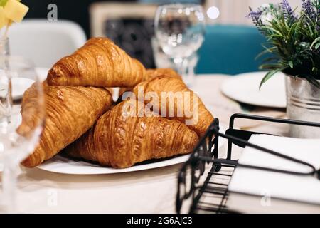 Close up photo of a pile of freshly-baked croissants on a plate sitting on the table Stock Photo