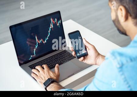 Business man trader investor analyst using mobile phone app and laptop rear view Stock Photo