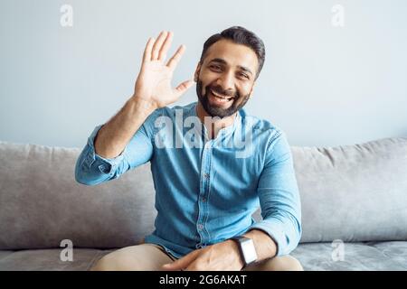 Headshot portrait of handsome indian man with friendly smile waving to camera Stock Photo