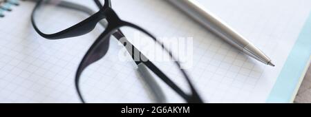 Black-framed glasses, pen, notebook lie on table Stock Photo