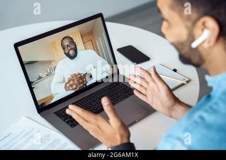 Afro american man talking using webcam internet connection, view over shoulder Stock Photo