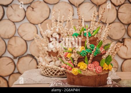 Two pies, decorative multi-tiered pastries with multi-colored cream flowers roses on a wooden background. Stock Photo