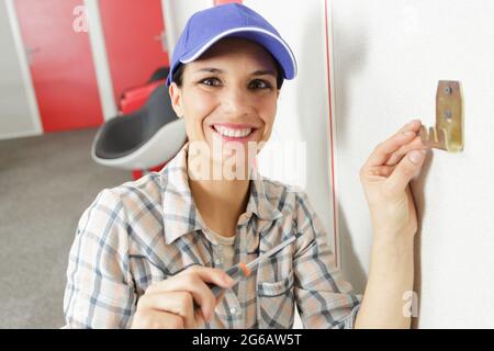 woman worker fitting a hook on the wall Stock Photo
